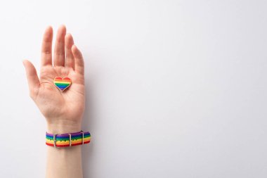 LGBTQ Tarih Ayı 'nı gökkuşağı renginde bileklik takan ve beyaz bir arkaplanda yazı veya reklam için yeri olan kalp şeklinde rozet taşıyan ilk kişi ile birlikte anıyoruz.