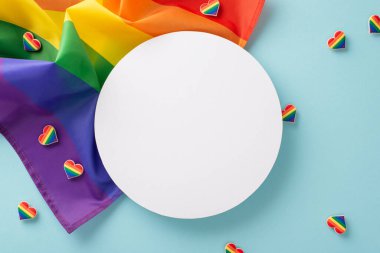 Sembolik bir LGBT Tarihi Ay geçit töreni aksesuarı. Gökkuşağı bayrağının üst görüntüsü, rozetler, renkli kalpler, metin ya da reklamlar için alanı olan mavi bir arkaplanda düzenlenmiş.