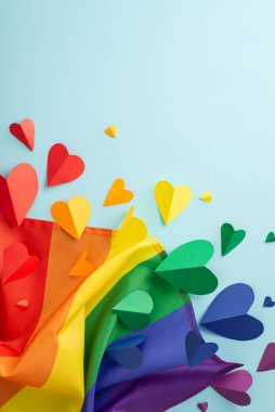 LGBTQ geçit töreni konsepti üst görünümde sembolik aksesuarların düzenlenmesiyle, bir gökkuşağı bayrağı, ve metin için boş alan ile açık mavi arkaplan üzerinde kalpler yer alır.