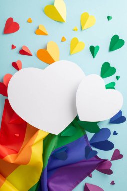 Dikey düz bir LGBTQ + geçit fikri, bir gökkuşağı bayrağı ve renkli kalpler, bir pastel mavi zemin üzerinde serilmiş, mesaj veya reklam için boş bir boşluk ile bir çift beyaz kalp