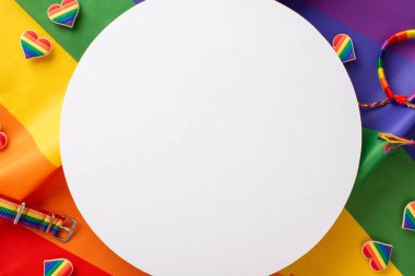 Çok renkli bir bilezik, bileklik, kalp şeklinde rozetler ve mesaj veya reklamlar için mükemmel boş bir daire şeklinde gökkuşağı arkaplanındaki LGBTQ geçit aksesuarları.