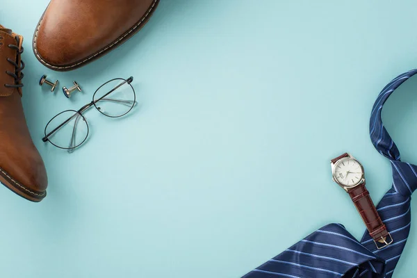 stock image Classy Father's Day concept. Flat lay top view of silk necktie, leather shoes, wristwatch, spectacles, cufflinks, male accessories on pastel blue background with blank space for text or advertisement
