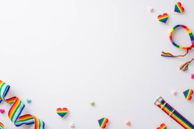 Bileklik, bilezik, gökkuşağı renkli kurdele, kalp şeklindeki incik boncuklar ve rozetler gibi LGBT geçit töreninin sembolik öğelerinin açık bir yüzey üzerinde metin veya reklam için düzenlenmiş beyaz bir yüzey üzerinde üst görüntüsü