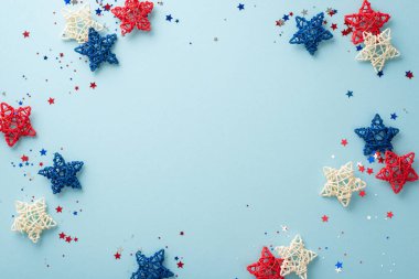 Bağımsızlık Günü şenliklerinizi sembolik parti aksesuarlarıyla yükseltin: rattan yıldızları ve ışıltılı konfeti. Pastel mavi arkaplan üzerindeki üst görünüm düzenlemesi metin veya reklamlar için boş alan içerir