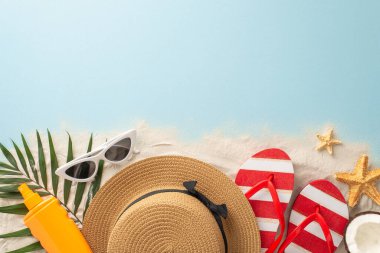 Tropik plaj kaçamağı teması. Plaj malzemelerinin tepe noktası: güneş gözlüğü, güneş gözlüğü, sandalet, güneş kremi, deniz yıldızı, palmiye yaprağı, taze hindistan cevizi. Metin için boş alan veya kumlu ve okyanus zemininde reklam