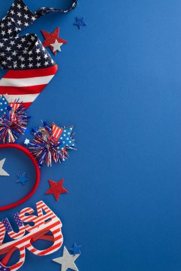 ABD temalı parti konsepti. Parlayan yıldızlar, vatansever saç bandı, parti gözlüğü, şık kravat gibi parti elementlerinin dikey üst görünümü, metin için boş bir arkaplan ile mavi arkaplan üzerine kuruludur.
