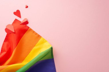 Gökkuşağı bayrağı ve kağıt kalpler gibi LGBT Gurur Ayı aksesuarları düz bir görünüm yatıyordu mesaj veya reklam için boş bir alan ile pastel pembe bir zemin üzerinde