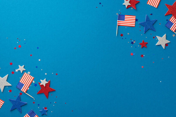 Верхний вид патриотических украшений: блестящие звезды, конфетти и национальные флаги, означающие День независимости США. Представлено на синем фоне с пустым местом для текста или рекламы