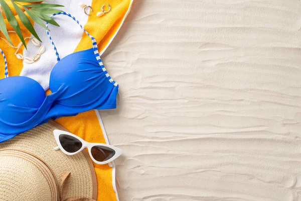 stock image Ready for a bright beach getaway. Top view of summer accessories: sunglasses, sunhat, swimsuit, towel, shell bijouterie, palm leaves. Sandy shore backdrop with an empty space for text or ads