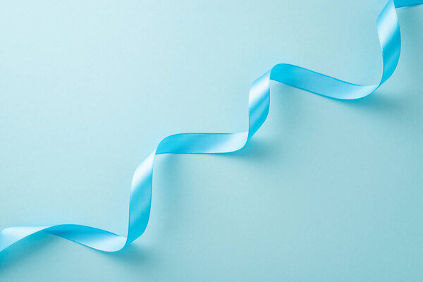 Top view photo of light blue twisted ribbon on a pastel background with copy-space