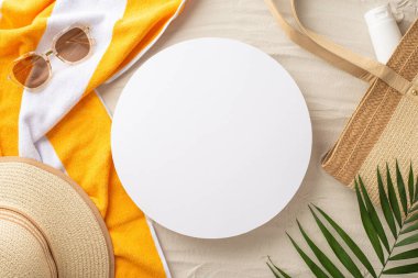 Tropik tatil konsepti. Temel gereksinimlerin genel görüntüsü: güneş gözlüğü, güneş gözlüğü, plaj çantası, güneş kremi, havlu, avuç içi yaprakları, kumlu arka planda mesaj veya promosyon için boş çemberle birlikte.
