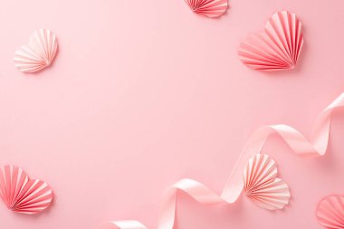 Üst manzara boş bir yer, pastel pembe kurdele ve kağıt origami kalplerle izole edilmiş açık pembe arka plan, kopyalanmış