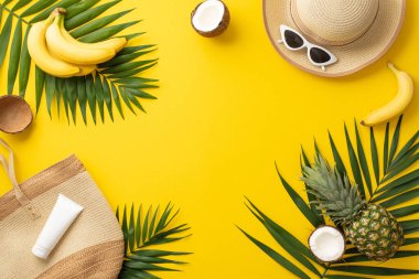 Hoş geldin yaz tatili. Plaj çantasının üst görüntüsü, güneş gözlüğü, güneş gözlüğü, güneş kremi şişesi, palmiye yaprakları, canlı sarı arkaplan üzerinde sulu tropikal meyveler metin ya da promosyon malzemesi için alan