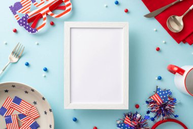 Bağımsızlık Günü hazırlıklarıyla masana biraz vatanseverlik ekle. Üst tabaka, kupa, çatal bıçak, peçete, serpinti, saç bandı, gözlük, Amerikan bayrakları, açık mavi fon. Resim için boş fotoğraf çerçevesi