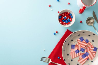 Bağımsızlık Günü temalı masa düzeninde vatansever aksesuarlar, tabak, fincan, çatal bıçak takımı, peçete, serpiştirilmiş çay tabağı, Amerikan bayrakları yer alıyor. Açık mavi arkaplanda üstteki görünüm metin veya reklam için boşluk