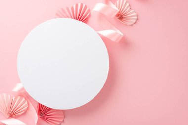 Boş beyaz çemberin en üstteki fotoğrafı. Pastel pembe kurdeleli ve kağıt origami kalpli. Ayrı bir açık pembe arkaplan ve kopyalanmış.