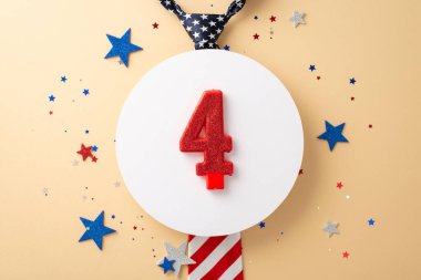 Üst görüntüde Amerikan bayrağı motifi ile süslenmiş bir kravat, beyaz daire üzerindeki dört numaralı mum, bej bir yüzey üzerinde sunulan yıldızlar ve konfetiler de dahil olmak üzere parıldayan süslemeler yer alıyor.
