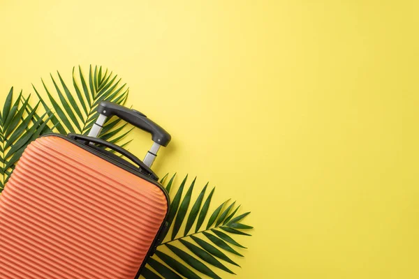 stock image Summer excursion idea. Top view of an orange suitcase, and palm fronds on vivid yellow background, providing an empty space for text or advertising