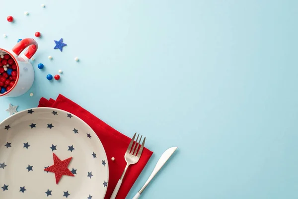 stock image Captivating top view of table set for celebrating Independence Day, adorned with patriotic accessories: plate, cutlery, napkin, sprinkles in mug, stars. Pastel blue backdrop with empty space for text