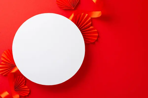 stock image Top view photo of white empty circle surrounded by bright red ribbon and paper origami hearts on isolated red background with copy-space