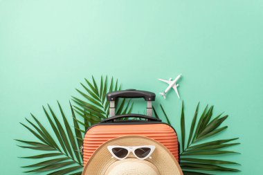 Sergilenen turuncu bavul, mini uçak, plaj gereçleri, güneş gözlüğü, güneş şapkası, palmiye yaprakları. Seyahat reklamları için ideal.