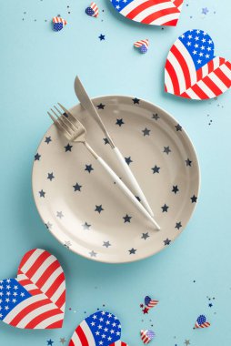Bağımsızlık Günü 'nü kutlamaya hazır olun! Özel durumlar için hazırlanmış tabağın dikey yukarıdan görünüşü, gümüş takımlar, Amerikan bayrak desenli kalpler ve konfeti gibi şenlikli dekorasyonlar.