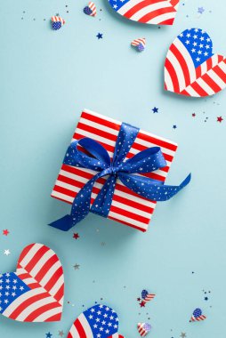 4 Temmuz kutlamanız kutlu olsun. Amerikan bayrak desenli kalpleri, konfetileri ve tematik ambalajda büyük hediye kutusunu içeren vatanseverlik temalı dekorasyonların dikey genel çekimi.