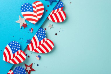 Gaziler Günü ABD yaratıcı kutlamaları. Vatansever süslemelerin üst görüntüsü: Amerikan bayrak deseniyle süslenmiş kalpler, parıldayan yıldızlar, çift renkli mavi yüzey üzerindeki konfeti yazı veya reklam için boşluk