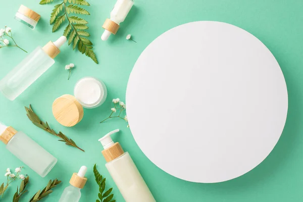 Eco-friendly cosmetic products concept. Above view photo of empty circle with cosmetic containers, bracken and eucalyptus branches and gypsophila on isolated turquoise background with copyspace