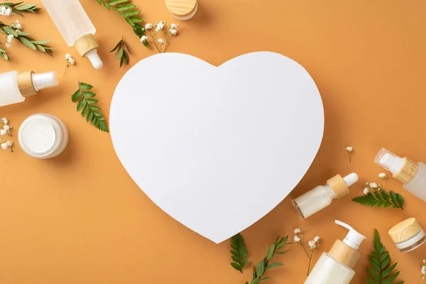 Natural herbal cosmetics concept. Above view photo of heart-shaped frame with bracken and eucalyptus foliage, gypsophila flowers and cosmetic containers on isolated brown background with copyspace