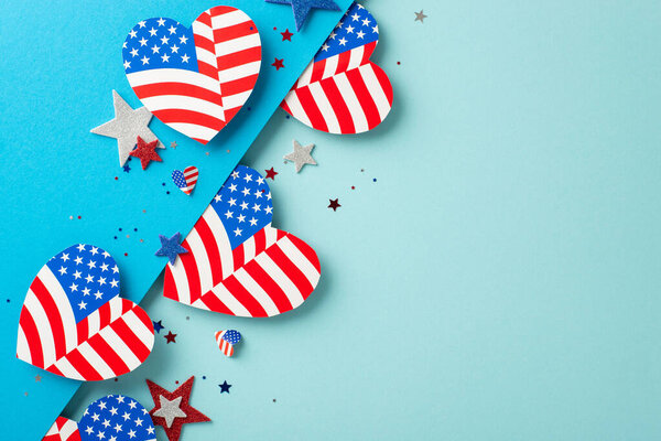 Veterans Day USA imaginative celebrations. Top view of patriotic adornments: hearts decorated with American flag pattern, glittering stars, confetti on bicolor blue surface with space for text or ad