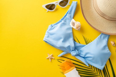 Güvenli güneş banyosu konsepti. Güneş kremi şişesi, şık güneş gözlüğü, güneş gözlüğü, mavi korse, deniz kabuğu, denizyıldızı, canlı sarı arka planda reklam için alan olan palmiye yaprağı.