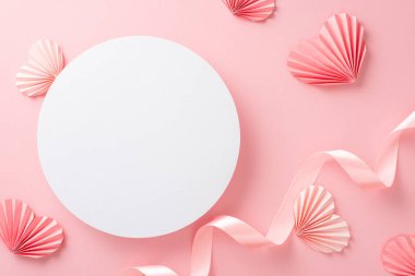 Boş beyaz çemberin en üstteki fotoğrafı. Pastel pembe kurdeleli ve kağıt origami kalpli. Ayrı bir açık pembe arkaplan ve kopyalanmış.