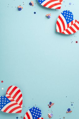 Birlik kutlaması. Sembolik süslemelerin dikey üst görünümü: Amerikan bayrağı deseniyle süslenmiş kalpler ve metin veya reklamlar için boş bir alan içeren pastel mavi bir arkaplan üzerindeki konfeti