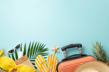 Rüya gibi bir plaj tatili. Turuncu bavul, plaj çantası, gözlükler, güneş şapkası, korse, güneş kremi, parmak arası terlikler, pastel mavi arka planda deniz yıldızı ve palmiye yaprakları, metin veya promosyonlar için mükemmel.