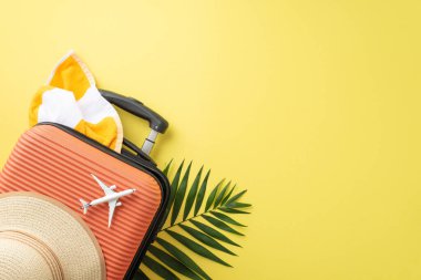 Yaz saadetine dal! Üst manzara valizi, minyatür uçak, güneş şapkası, havlu ve sarı arkaplanda palmiye yaprakları gibi temel plaj eşyaları. Seyahat reklam potansiyelinizi açık alanda serbest bırakın