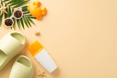 Bebekle birlikte İdilik plaj inzivası. Etiketsiz SPF krem şişesi, yengeç kumu kalıbı, modaya uygun güneş gözlükleri, lastik sandaletler, yumuşak bej arka planda palmiye yaprağı. Tanıtım malzemesi için boş alan