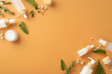 Doğal bitkisel kozmetik kavramı. Ayraç ve okaliptüs yapraklarından yapılmış boş çerçeve fotoğrafı, alçıtaşı çiçekleri ve kopyalanmış kahverengi arkaplan üzerindeki kozmetik kaplar