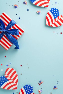 Amerika 'da Bağımsızlık Günü' nü kutluyoruz. Amerikan bayrağı tasarımı, konfeti, tematik hediye kutusu, metin veya tanıtım için boş alanı olan pastel mavi yüzey gibi sembolik süslemelerin dikey üst görünümü
