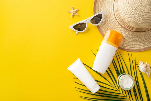 Güneş güvenlik düzenlemesi. Üst görünümde güneş kremi, etiketsiz SPF krem şişeleri, gözlük, şapka, kabuk, deniz yıldızı, parlak sarı arkaplan üzerinde palmiye yaprağı metin veya reklam için boş alan