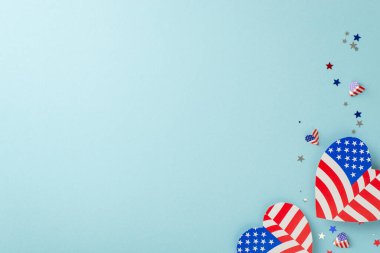 4 Temmuz 'u kutluyoruz. Temsili süslemelere yukarıdan bir bakış: Amerikan bayrağı tasarımı ile süslenmiş kalpler, parlak konfeti, tanıtım için yer ile birlikte pastel mavi arka planda düzenlenmiş