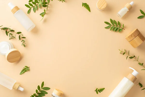 stock image Natural cosmetic products concept. High view photo of empty place surrounded by cosmetic containers, eucalyptus and fern foliage on isolated beige background with copy-space