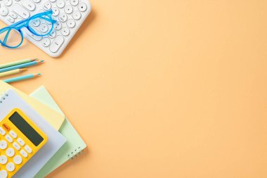 Okul yılına baştan çıkarıcı üst görünüm görüntüsüyle başla. Düzgün düzenlenmiş okul gereçleri, gözlükler, klavye, planlayıcılar, hesap makinesi, yumuşak turuncu arkaplan üzerindeki kalemler, özel metin veya reklam için yer açılmasına olanak sağlıyor