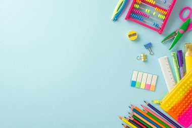 Bu yukarıdaki fotoğrafla öğrenmenin zevkini keşfedin: izole edilmiş bir pastel mavi yüzey üzerinde renkli okul malzemelerinin hoş bir düzenlemesi, metin veya reklamlar için telif alanı ile
