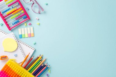 Üst görünüm kompozisyonunda düzenlenmiş zevkli eğitim gereksinimleri: huzurlu bir pastel mavi arka planda canlı renkli materyallerin bir çeşidi, metin veya reklam için kopyalanacak yer sağlar