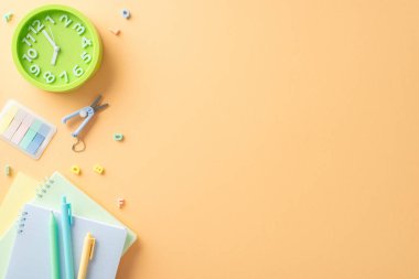 Sınıfa hoş geldin. Düzgünce düzenlenmiş kırtasiye, makas, günlükler, saat, alfabe harfleri, yumuşak turuncu arka planda üst perdeden yakalanan diğer esaslar. Okula dönüş tanıtımı için mükemmel.