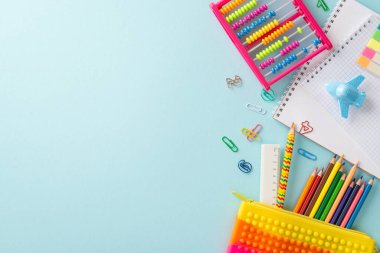 Bu üst görünüm ile öğrenmenin hazzını yaşayın: Pastel mavisi izole bir arkaplan karşısında zevkli okul malzemeleri dizisi, metin veya reklam için telif alanı sağlar