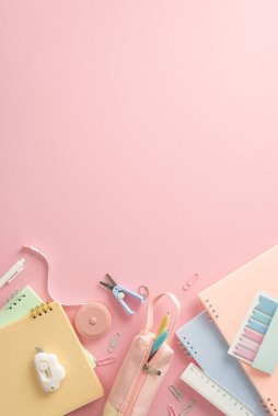 Okul kompozisyonu için hazır. Kırtasiye malzemesi, fotokopi kitapları, kalem kutusu, ataçlar, makas, yapışkan notlar, cetvel, bant, pastel pembe zemin üzerinde katiplik bıçağı, metin veya reklam için boşluk
