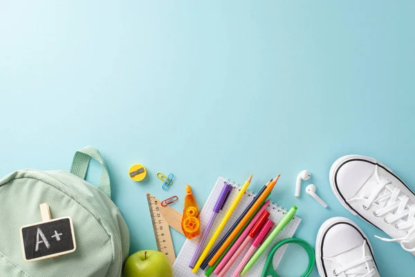 Academic journey concept. Creative overhead shot of backpack, pair of shoes, and various educational tools on pastel blue backdrop. Perfect for text or advertising purposes