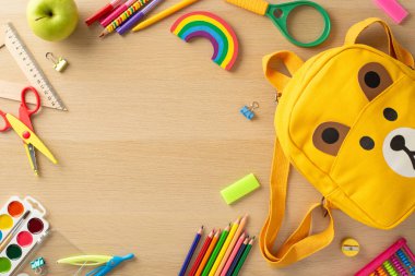 Okul malzemeleri sahnesi. Canlı aksesuarlar, sanat malzemeleri, makas, cetvel, keskinleştirici, büyüteç, abaküs, sevimli ayı şekilli çanta, elma ve daha fazlası ahşap masa üzerinde reklam için boş alan